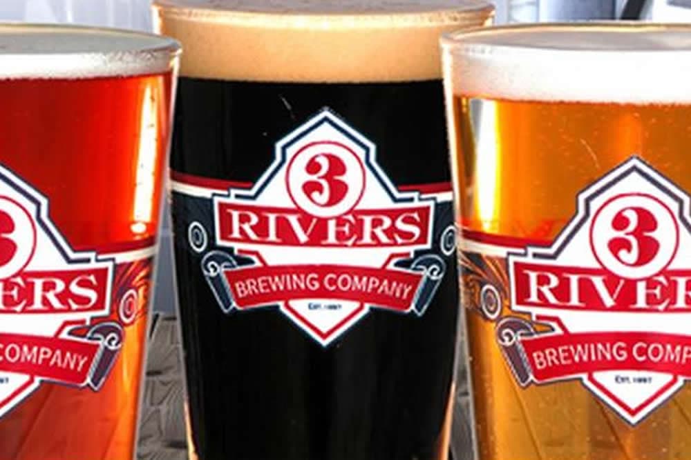 Three glasses of beer from 3 Rivers Brewing Company, featuring different colors and frothy tops.