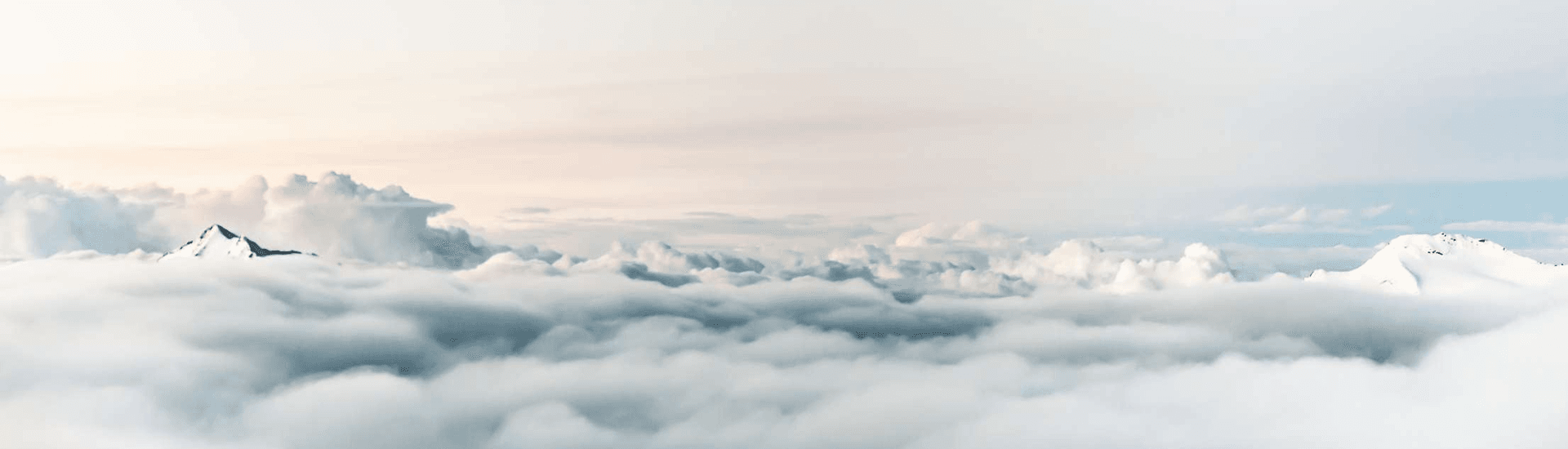 A panoramic view of mountains peeking above a sea of clouds.