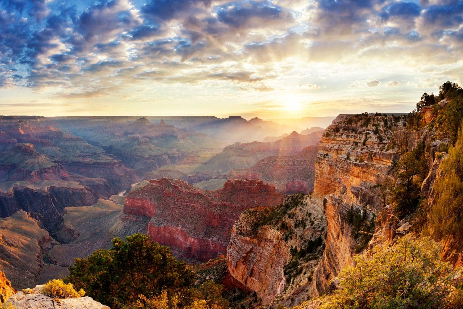 A stunning view of the Grand Canyon at sunrise, highlighting layered rock formations and a colorful sky.