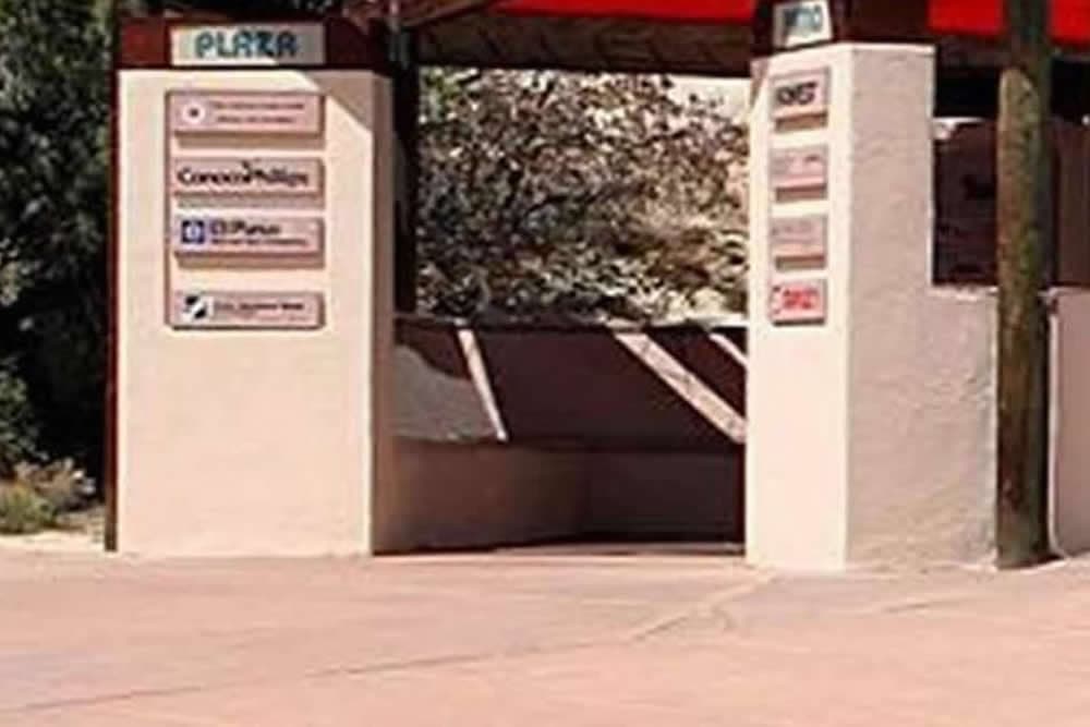 A desert plaza entrance with signage on the walls and a shaded overhang.
